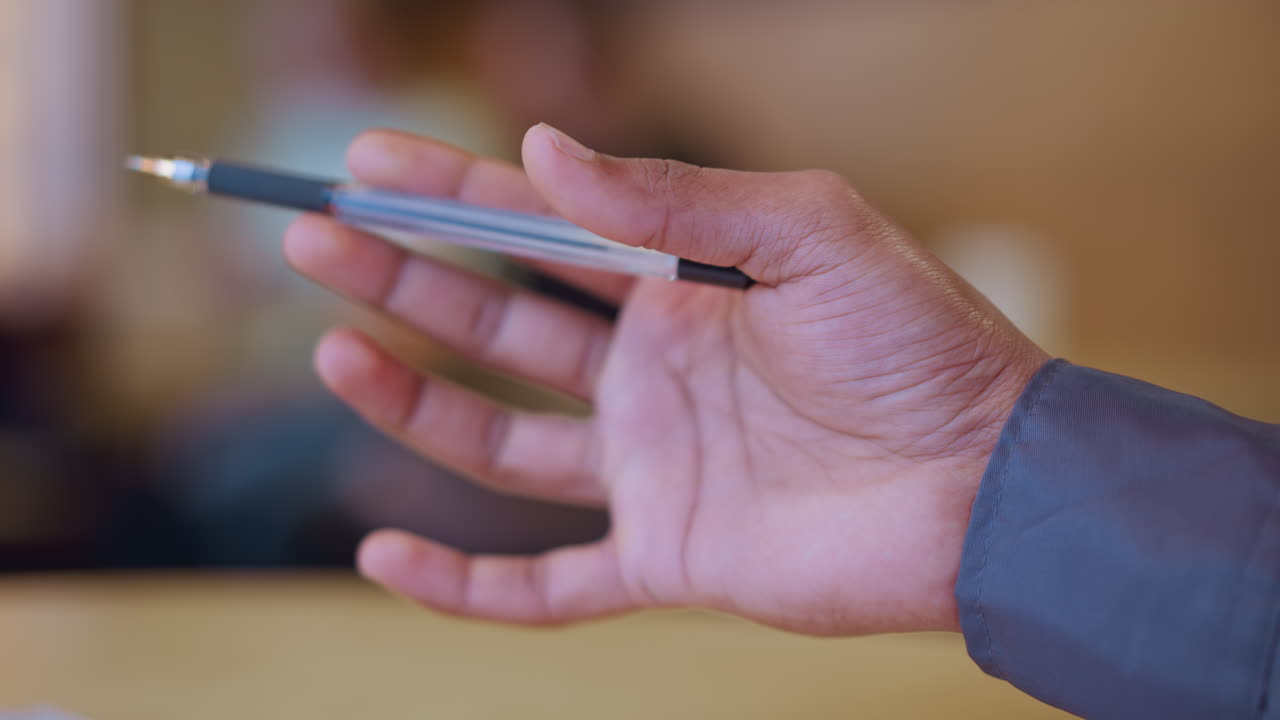 Close-up of male hand in mid-air gesture with relaxed fingers, captured in thoughtful or expressive motion, possibly emphasizing or illustrating point during discussion in warm indoor setting with blurred background