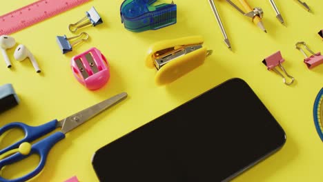 video of diverse office tools, tablet and smartphone with copy space on yellow background