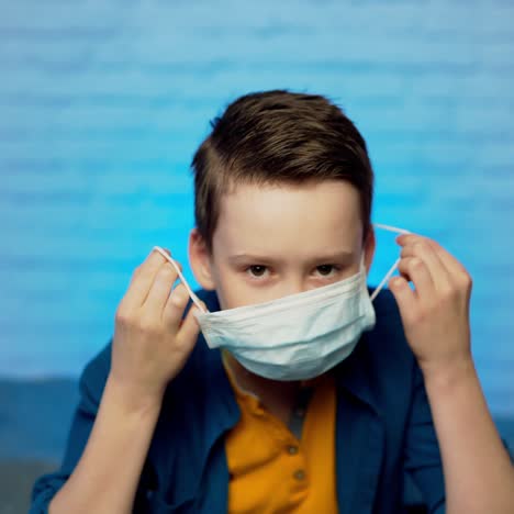 beautiful boy puts on face medical mask against bacteria and viruses. pandemic covid-19. quarantine in children. self isolation