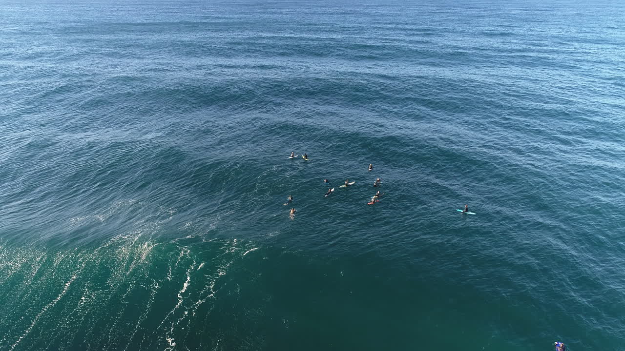 Smooth aerial tracking over blue green ocean surface with waves forming below