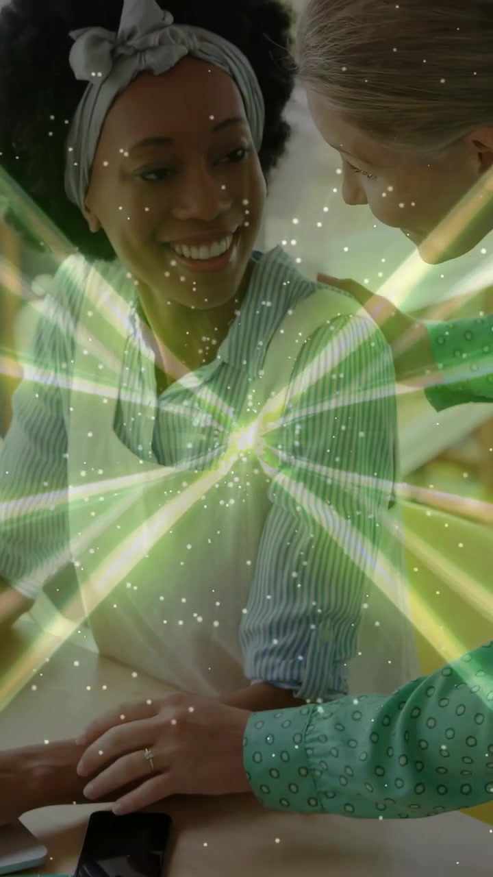 Video verticale: Mentore che guida un artigiano con la mano per imparare un mestiere usando il telefono, con sovrapposizione di un'esplosione di luce verde.