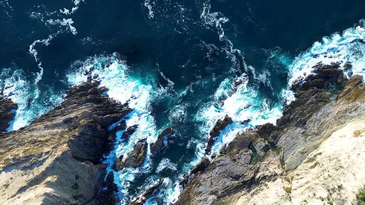 Paesaggio aereo da drone di profonde onde oceaniche e onde costiere che si infrangono lungo la costa rocciosa con insenatura e parete a strapiombo a Malua Bay, Australia, viaggi, turismo, vacanze, pesca, natura
