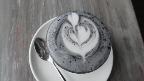 a cup of hot black charcoal latte art