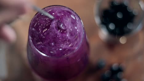 top-down show of a bartender stirring a vibrant purple drink before serving