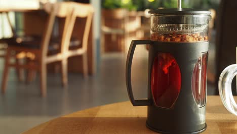 glass tea pot on wooden table in a cafe