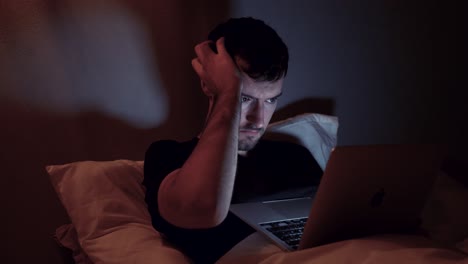 hombre con computadora portátil en la cama, internet en línea por la noche, trabajo tardío, navegación web, video viendo en el cuaderno antes de dormir