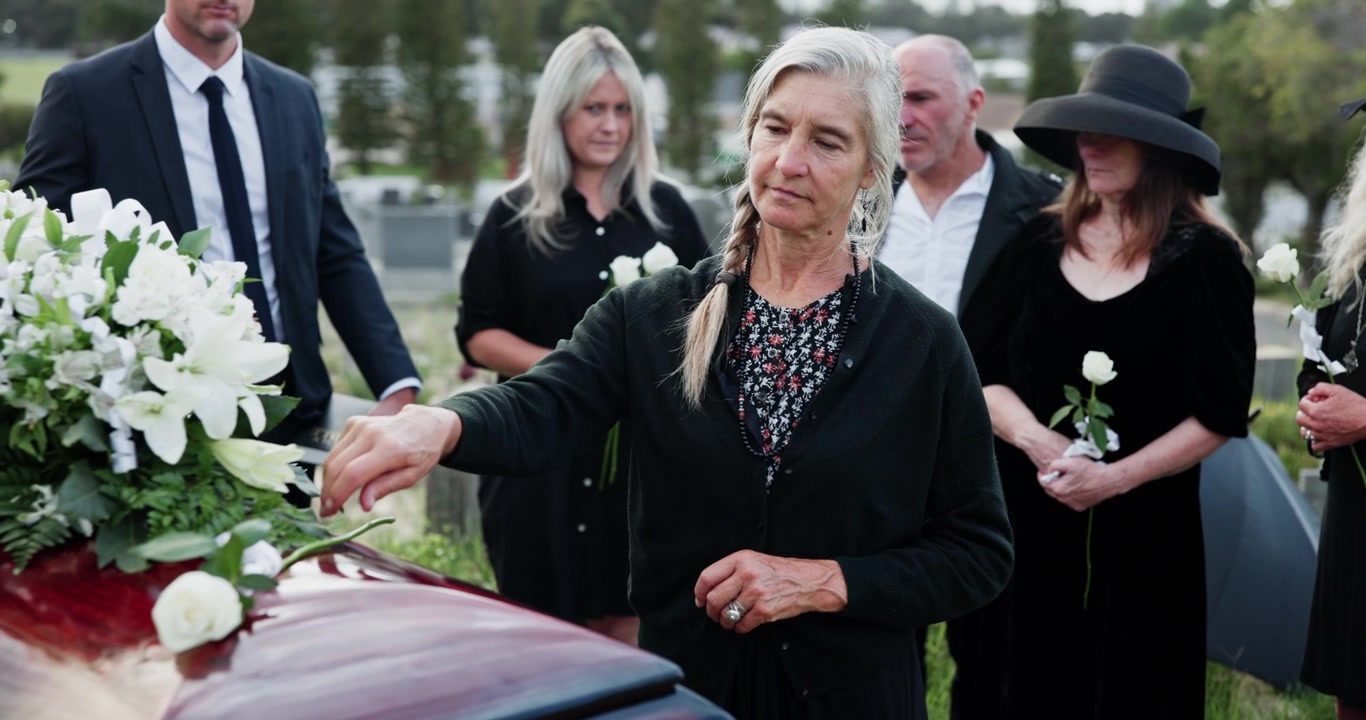 Donna in lutto che depone una rosa bianca sulla bara durante un funerale