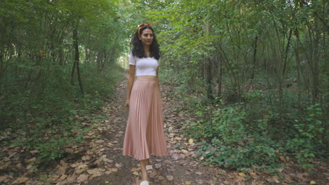 elegant young lady woman walking alone in nature park forest trail, dolly tracking outside shot of slim attractive girl walks and turns around, casual trendy fashion brunette stylish model