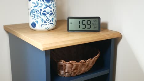 mesa de noche con reloj digital y canasta