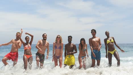 Front-view-of-mixed-race-friends-jumping-together-on-the-beach-4k