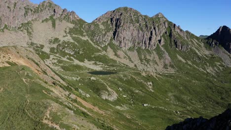 flying down towards a secluded lake in between mountains in the mountain range of lagorai, italy