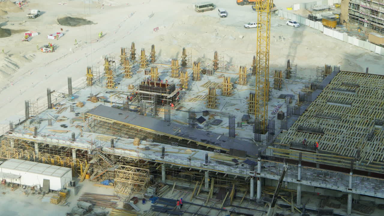Vista aerea di un cantiere edile in piena attività con operai e macchinari a Dubai.