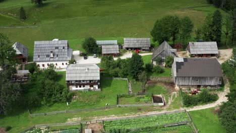 Aerial-view-of-Alpine-Valley-with-rustic-farm-in-front,-Jezersko,-Slovenia,-European-Alps,-scenic-mountain-landscape