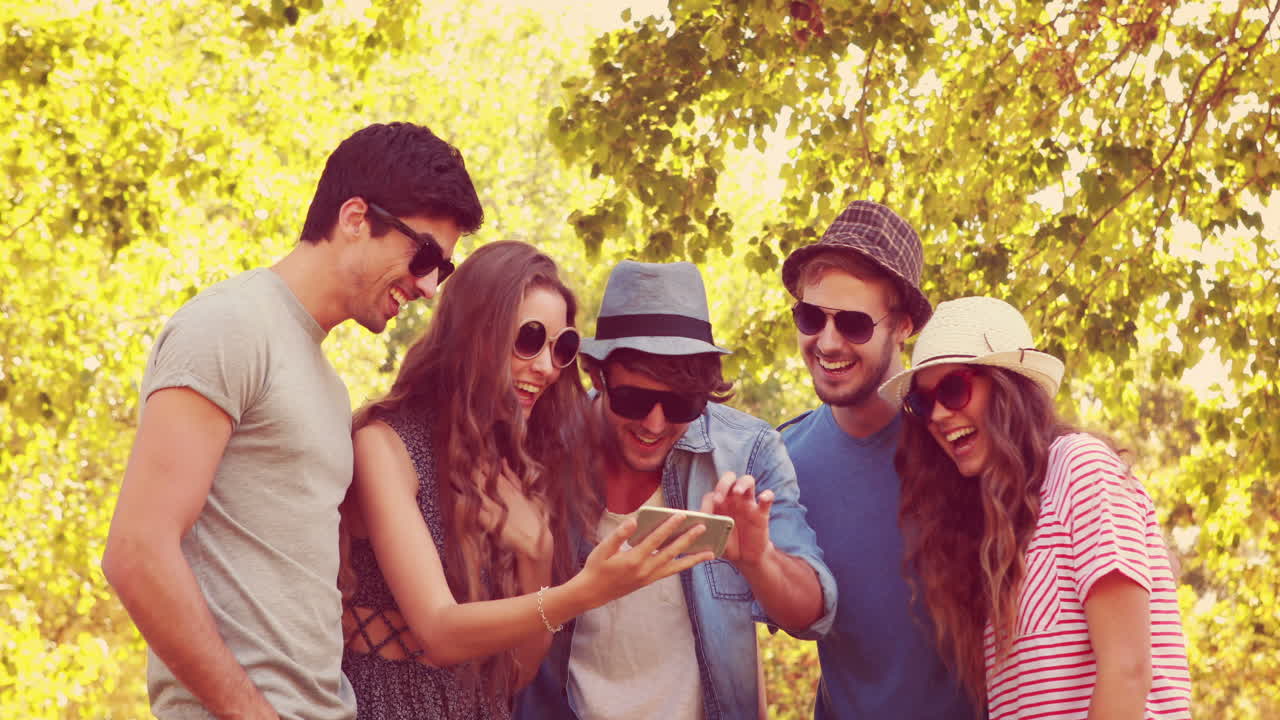 Amici felici che guardano foto su uno smartphone al parco