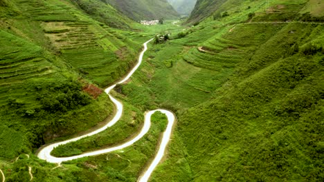 Aerial-shot-of-a-winding-road-making-it's-way-through-a-lush-green-valley-in-the-beautiful-ma-pi-leng-Pass