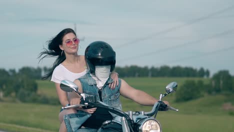 pretty brunette girl holds man in black helmet on motorbike