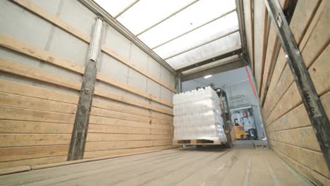 forklift driver transports packaged water bottles in warehouse