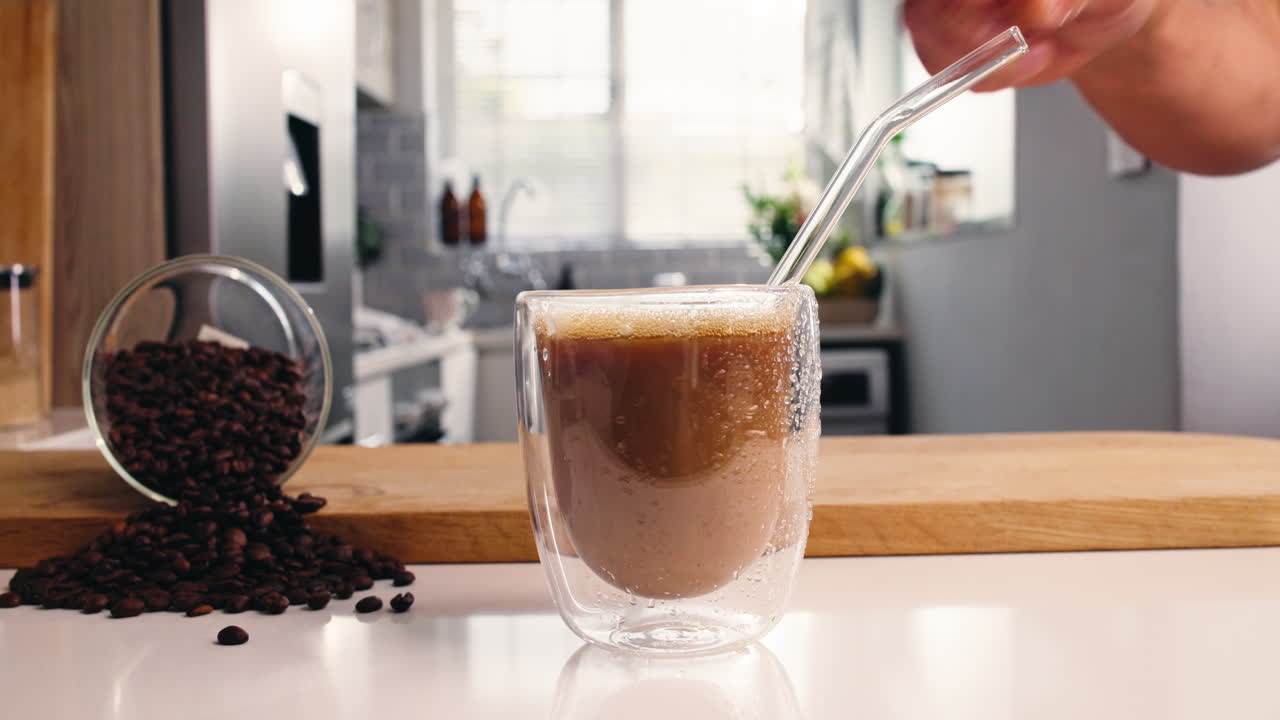 Caffè mescolato a mano con una cannuccia in una cucina moderna