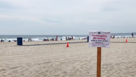 a sign on a san diego beach urging social distancing summer of 2020