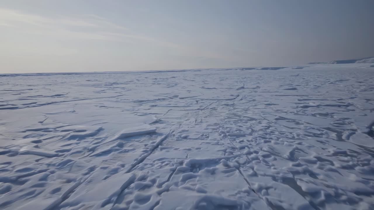 Low-angle video of a vast icy landscape with a dramatic crack, highlighting the raw, cold beauty