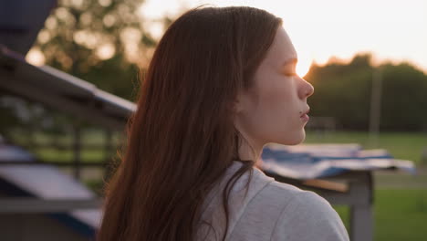 a young woman with long hair looks into the sunset.