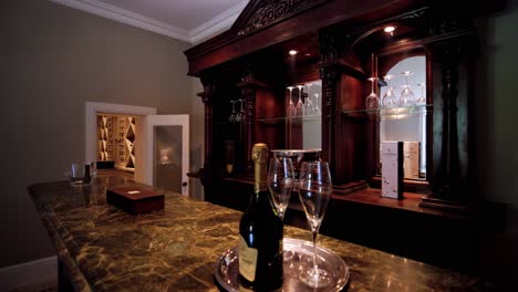 nicely decorated indoor household, granite stone bar table with wine bottle and glasses, stylishly furbished wooden furniture, french style house design