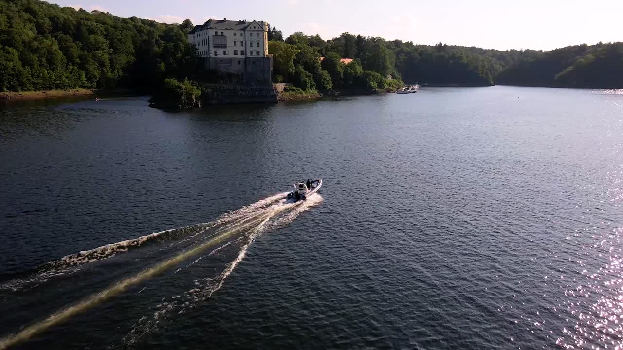 Inflatable boat speeding on the water surface with Orlik Castle view