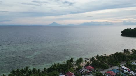 Aérea,-Estableciendo-Una-Toma-De-Drones-De-Una-Playa-Impresionante-Y-Un-Barangay-Pintoresco-Con-La-Silueta-Del-Volcán-Mayon-En-El-Fondo-Durante-El-Atardecer,-Catanduanes,-Filipinas