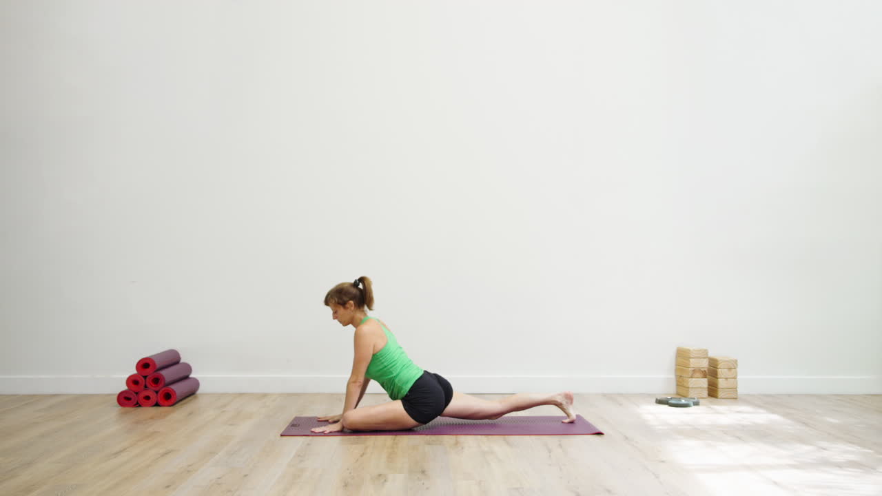 Woman Practicing Yoga Poses on a Mat in a Bright Studio