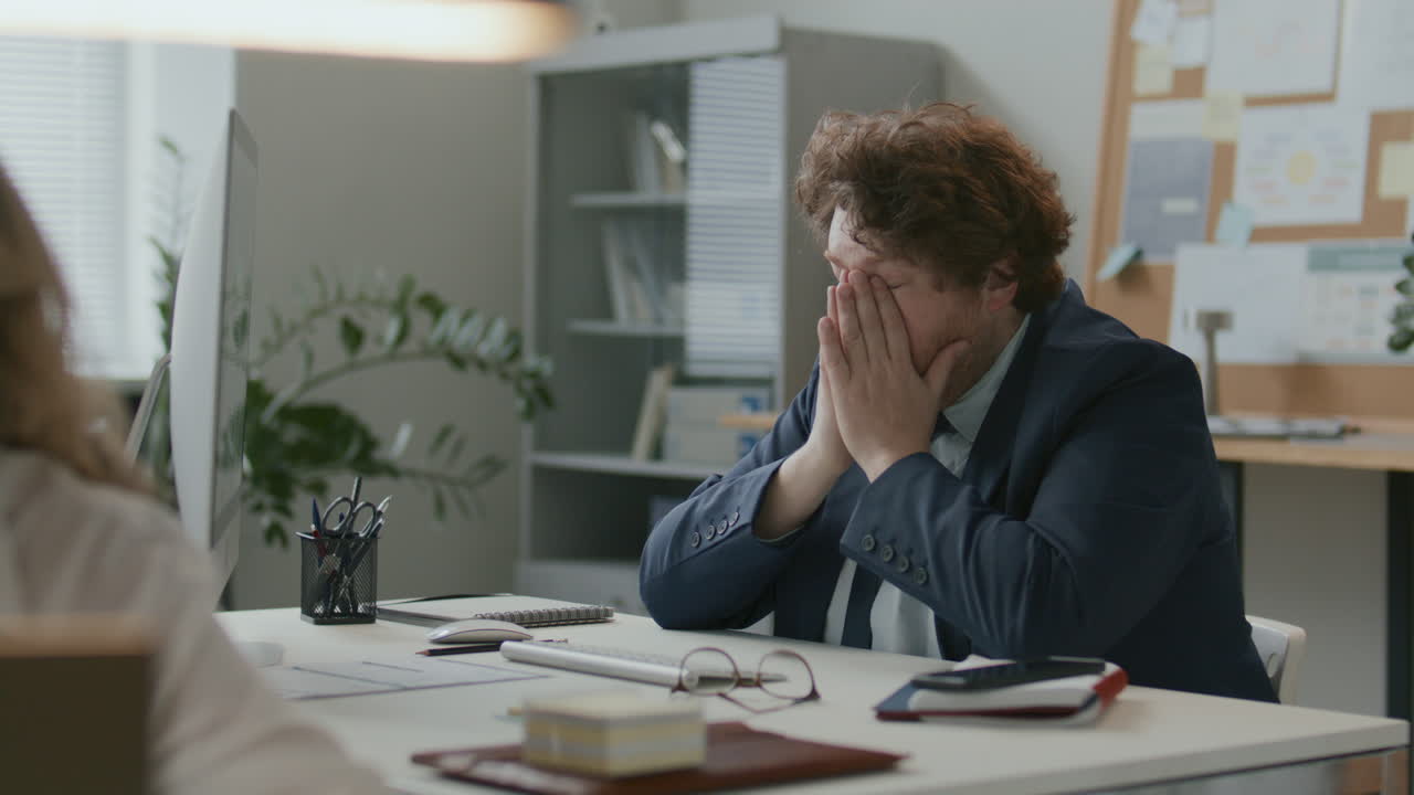Exhausted Businessman Working on Computer and Rubbing His Eyes at Office Desk