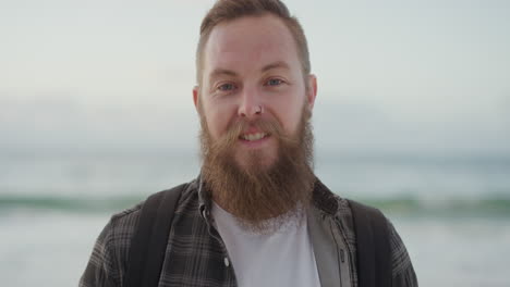 portrait of young bearded man smiling looking at camera on beach enjoying positive lifestyle handsome hipster male at seaside