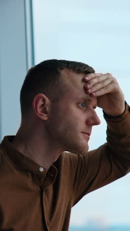 Young businessman looking through the window Vertical video