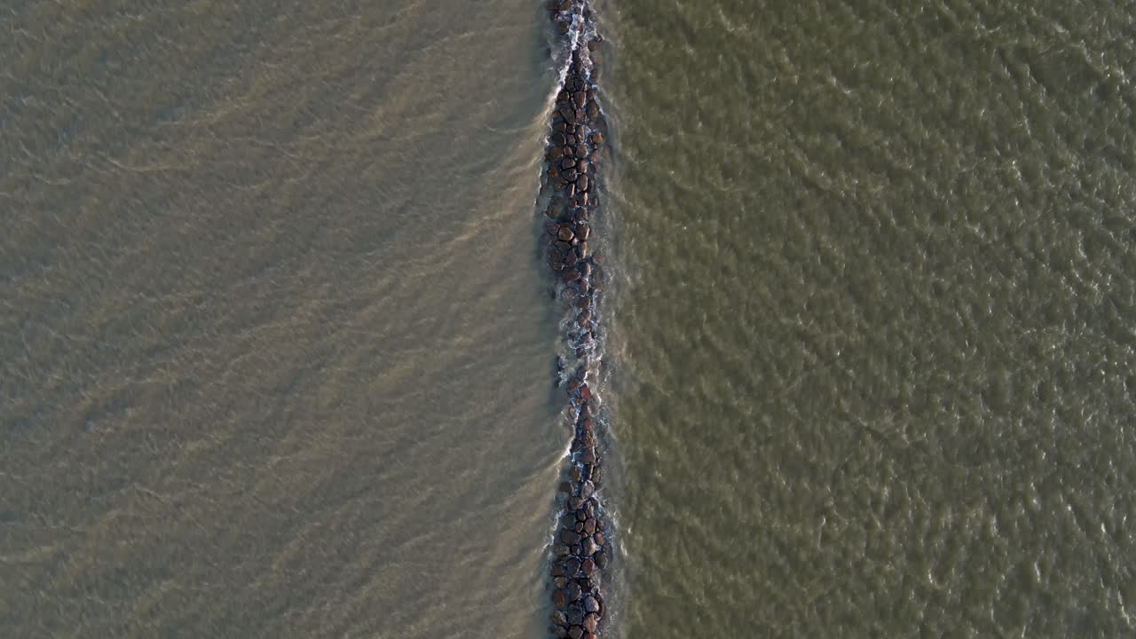 медленный полет, взгляд с высоты птицы на частично погруженный волнолом в море