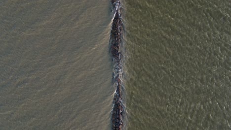 vuelo lento, vista de pájaro de un rompeolas parcialmente sumergido en el mar