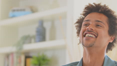 Retrato-De-Un-Joven-Sonriente-Relajándose-En-Casa-Sentado-En-La-Mesa