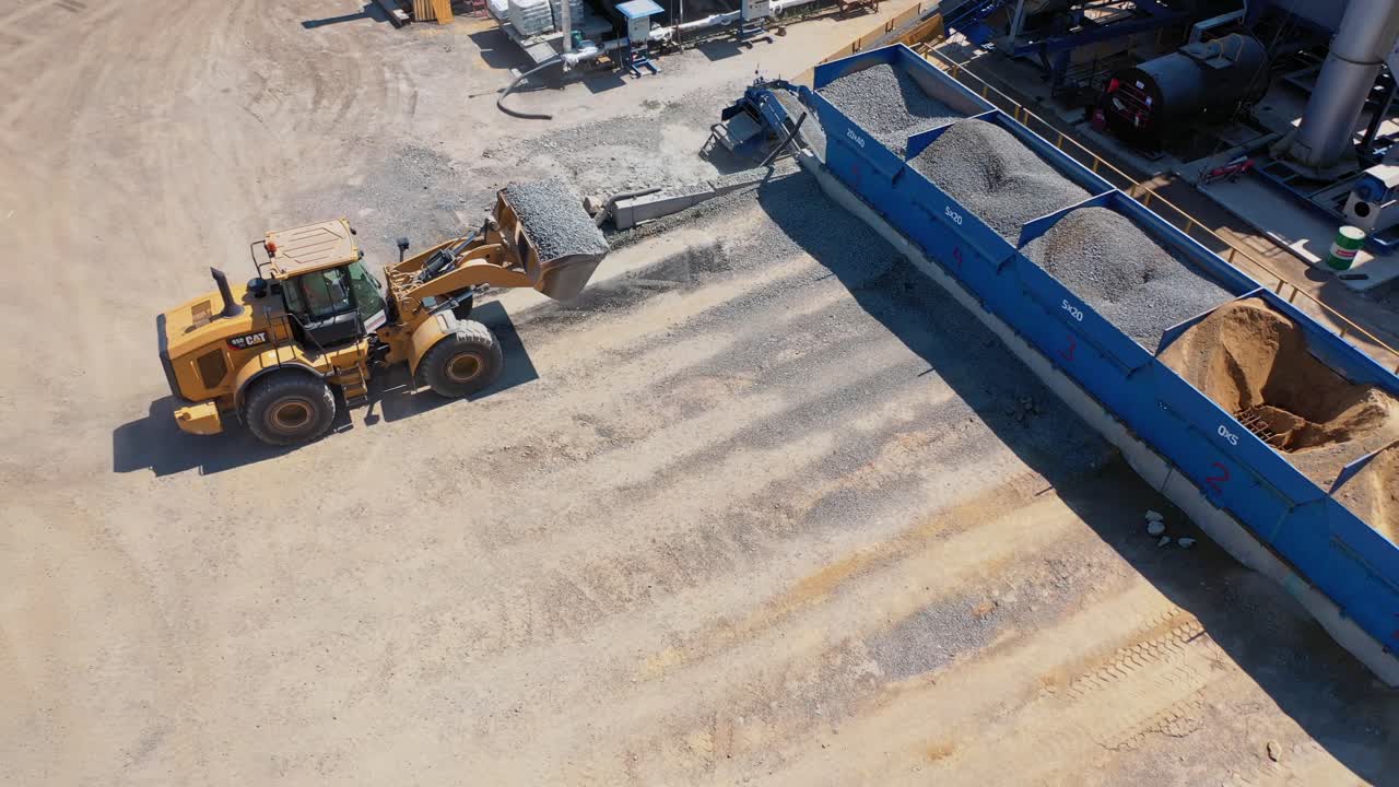 Heavy bulldozer loading sand. Aerial view of machinery and mine equipment near road on sandy surface