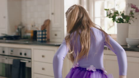 happy ballerina girl dancing in kitchen having fun practicing ballet dance moves wearing purple tutu at home