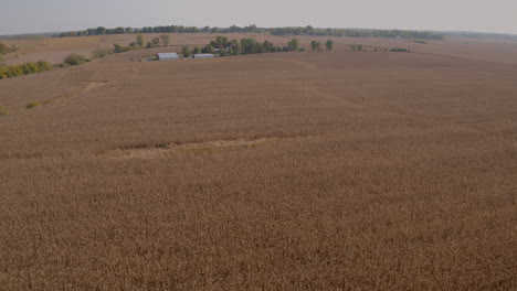 Flyover-farmland-in-the-midwest-past-a-beautiful-farm-house-and-towards-a-country-road