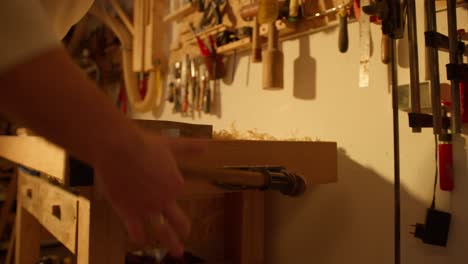 close up of man tightening a wooden plank by hand with a crank in a workshop