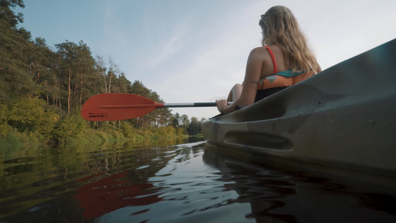 Low angle view of blonde girl paddling a