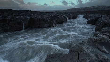 mysterious rapid river flowing between volcanic basalt landscape in iceland during grey sky,close up