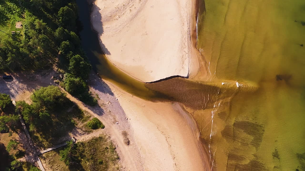 Drone top down of river inlet and sand banks merging with Baltic coastline in Latvia