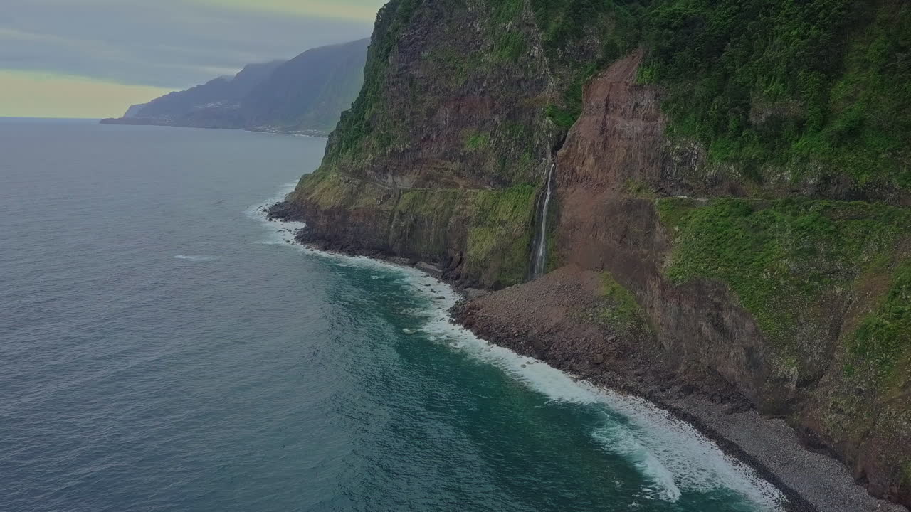 Aerial view as Véu da Noiva waterfall flows into the ocean from cliff, Madeira