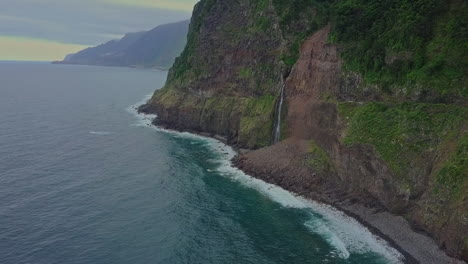 vista aérea mientras la cascada véu da noiva desemboca en el océano desde un acantilado, madeira
