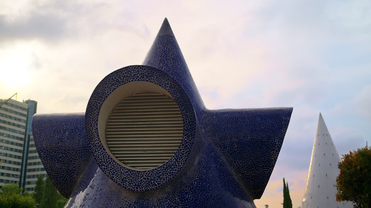 Close up of a star shaped blue mosaic ventilation structure with circular louver, white cone visible in background in the City of Arts and Sciences, Valencia, Spain