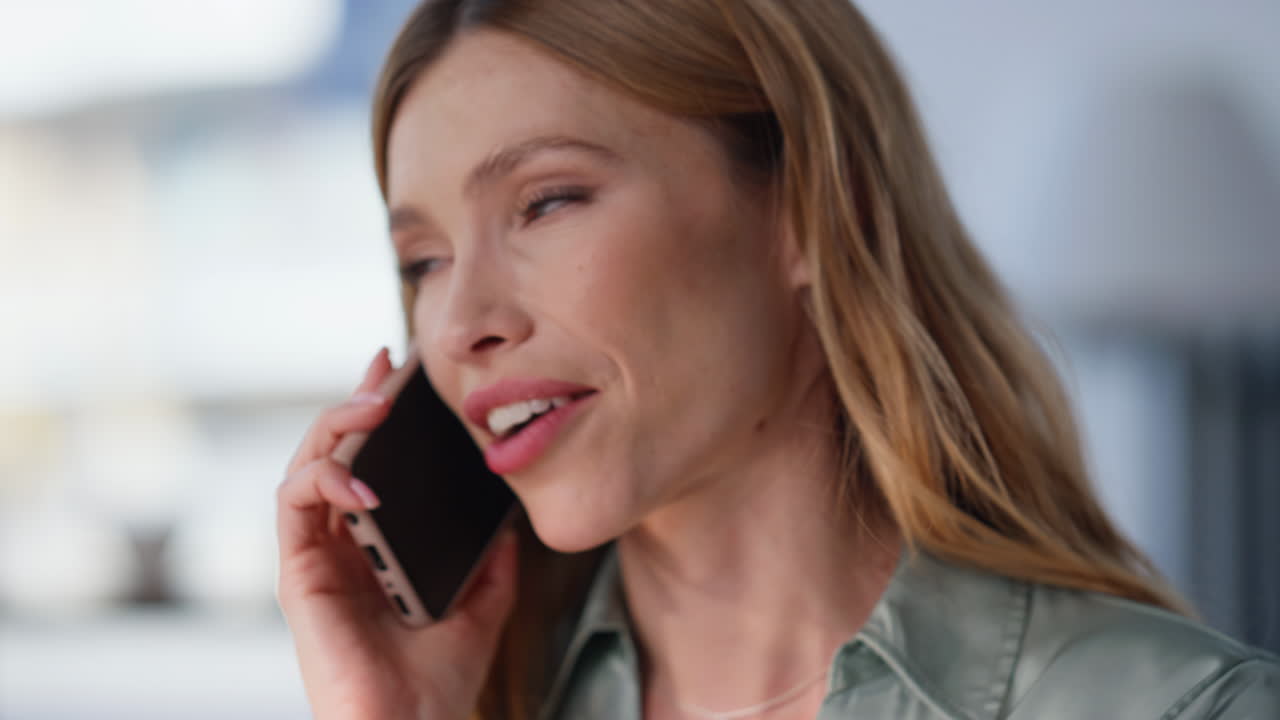 Closeup businesswoman talking cellphone discussing work sitting near window