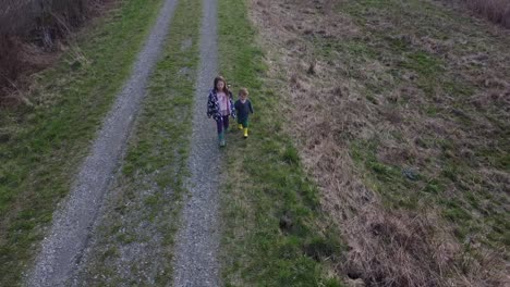 sweet siblings holding hands while walking with their colored boots in the park of monroe michigan  - aerial shot