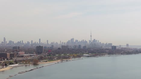 aerial: downtown toronto skyline during the day with mist and cityscape in ontario, canada, establishing drone shot