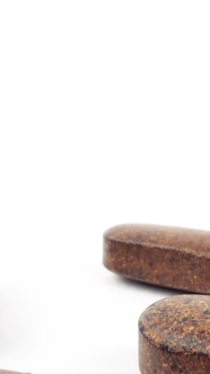 vista minimalista de tabletas marrones de hierbas esparcidas en una superficie blanca