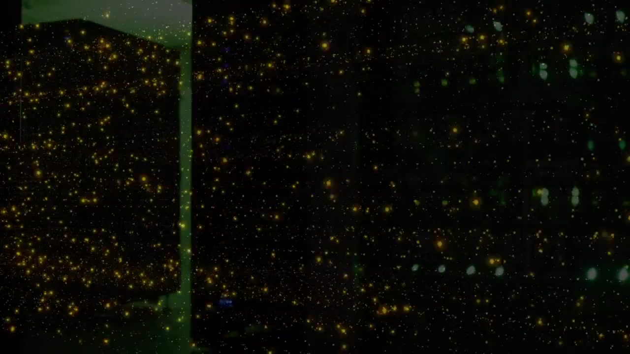Densas motas de oro reluciendo tras pequeños pulsos de luz, llenando un plano oscuro con un brillo reflectante.